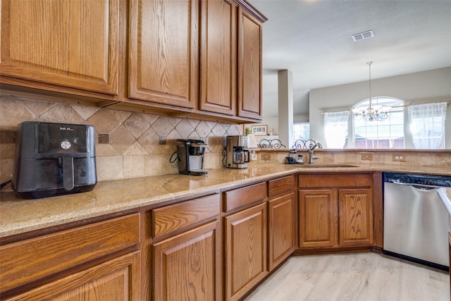 kitchen with brown cabinets, visible vents, dishwasher, and a sink