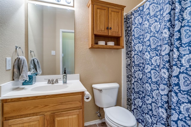 bathroom with a textured wall, vanity, and toilet