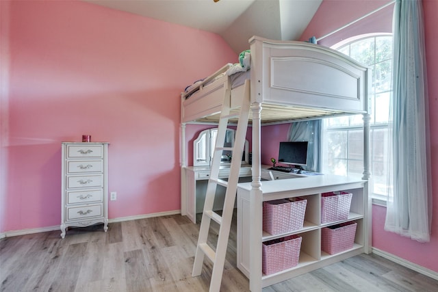 unfurnished bedroom with light wood-type flooring, vaulted ceiling, and baseboards