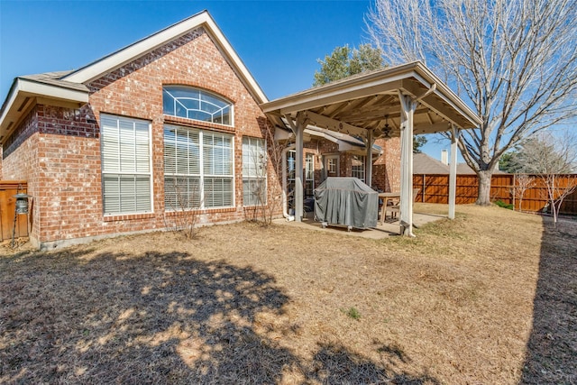 rear view of house with fence, a patio, and brick siding