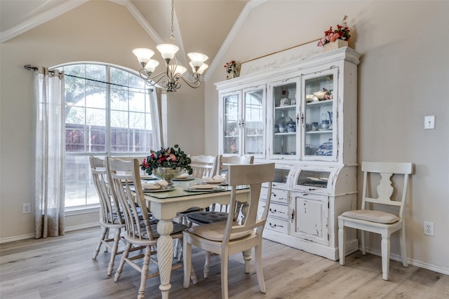 dining space with light wood-style floors, lofted ceiling, a notable chandelier, and crown molding