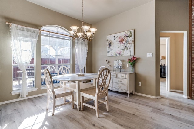 dining room with light wood finished floors, baseboards, and an inviting chandelier