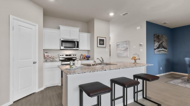 kitchen with a kitchen breakfast bar, stainless steel appliances, a sink, and wood finished floors