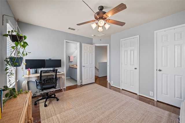 office area featuring ceiling fan, wood finished floors, visible vents, and baseboards