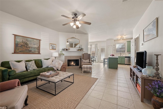 living area featuring light tile patterned floors, a tiled fireplace, and a ceiling fan