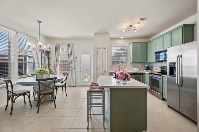 kitchen with light tile patterned floors, green cabinetry, stainless steel appliances, light countertops, and a notable chandelier