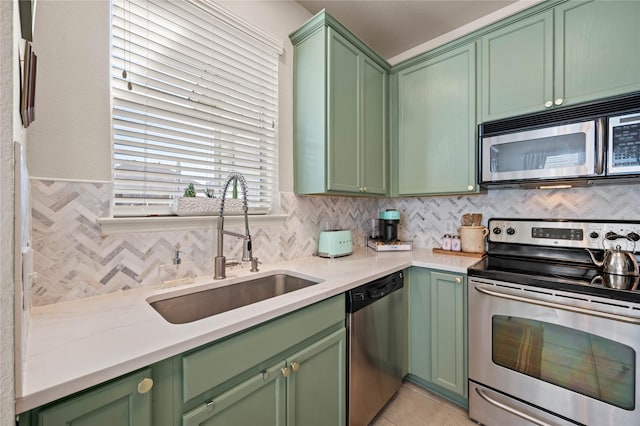 kitchen featuring green cabinets, appliances with stainless steel finishes, backsplash, and a sink