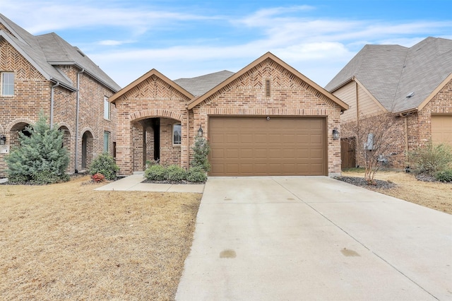 french country home with a garage, brick siding, and driveway