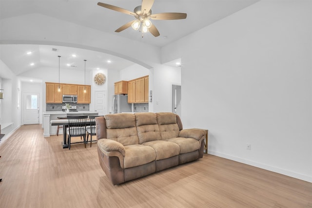 living room featuring arched walkways, ceiling fan, recessed lighting, baseboards, and light wood-type flooring