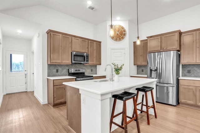 kitchen with visible vents, a sink, light wood-style floors, appliances with stainless steel finishes, and a kitchen breakfast bar