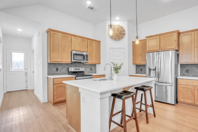 kitchen featuring a sink, visible vents, light countertops, appliances with stainless steel finishes, and light wood finished floors