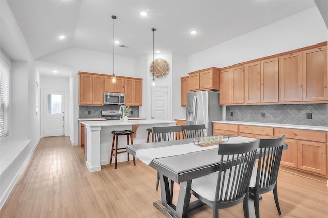 kitchen with an island with sink, a breakfast bar area, stainless steel appliances, light countertops, and light wood-type flooring