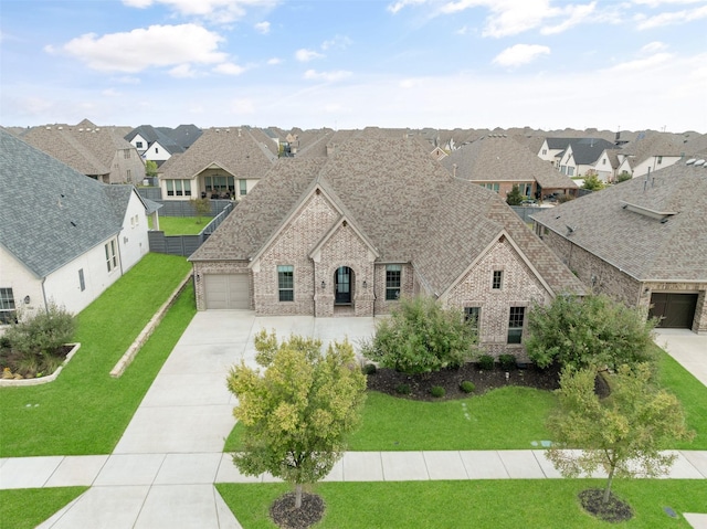 view of front of house featuring a shingled roof, brick siding, driveway, a residential view, and a front lawn