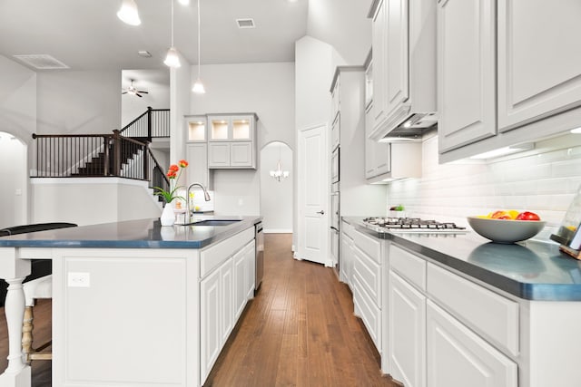 kitchen with a ceiling fan, dark countertops, dark wood-style flooring, a sink, and backsplash