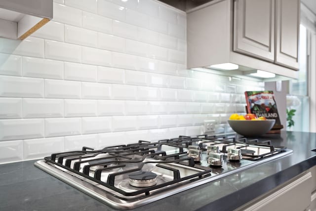 room details with dark countertops, stainless steel gas stovetop, and decorative backsplash