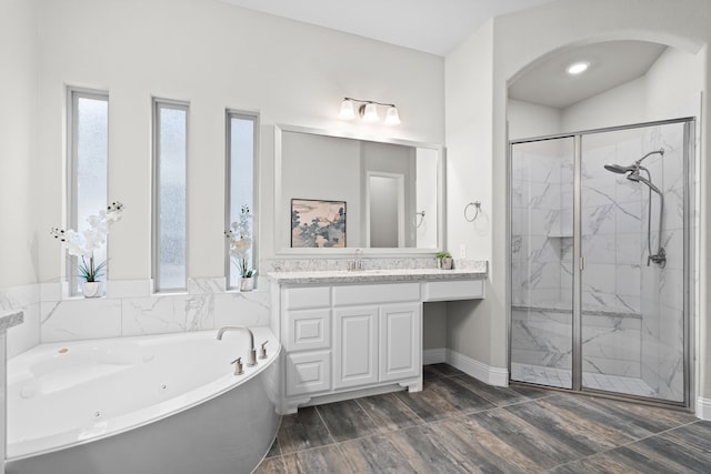 full bath with a whirlpool tub, vanity, a marble finish shower, and a wealth of natural light