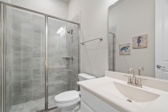 bathroom with a textured wall, a shower stall, toilet, and vanity