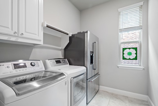 clothes washing area with light tile patterned floors, independent washer and dryer, cabinet space, and baseboards