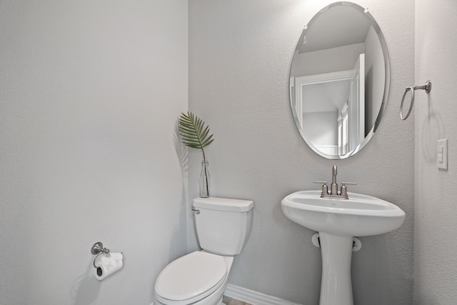 bathroom with baseboards and toilet