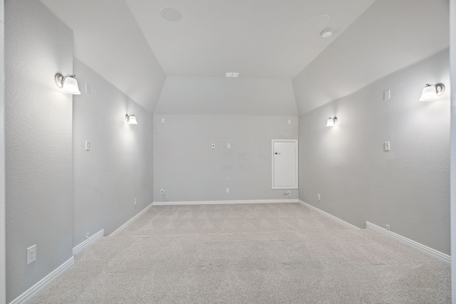 unfurnished room with vaulted ceiling, light carpet, and baseboards