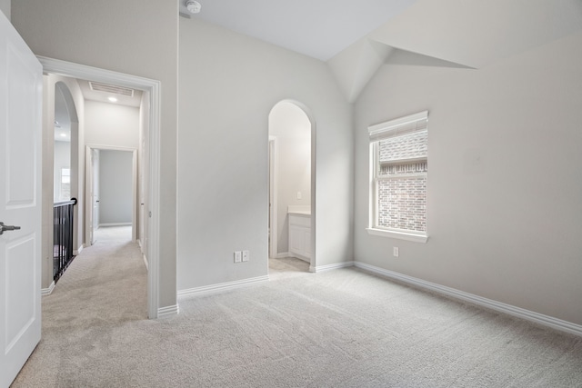 unfurnished bedroom featuring arched walkways, light carpet, vaulted ceiling, and visible vents