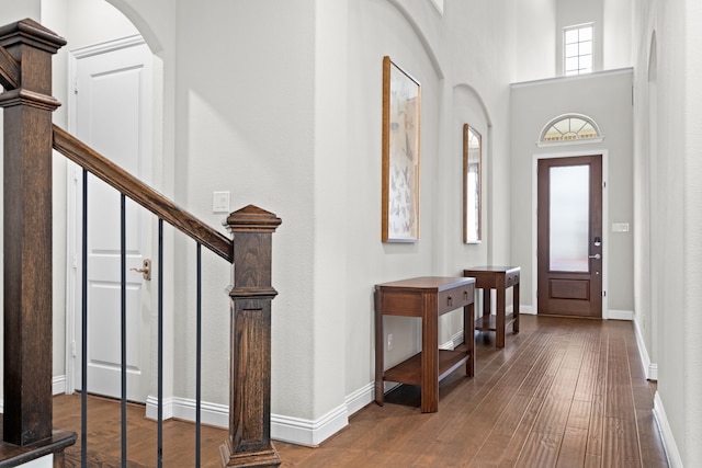 foyer entrance featuring stairs, hardwood / wood-style floors, arched walkways, and baseboards