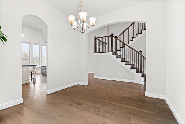 unfurnished dining area with a towering ceiling, stairway, baseboards, and wood finished floors