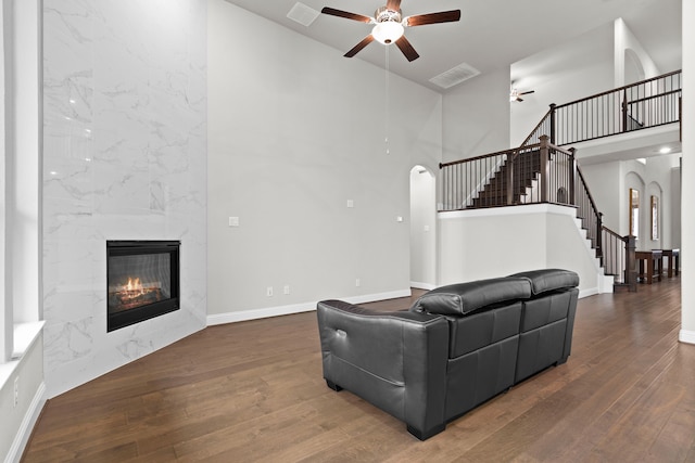 living room with arched walkways, a premium fireplace, visible vents, stairs, and hardwood / wood-style floors