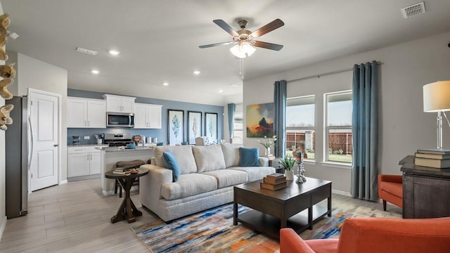 living area with light wood-style floors, ceiling fan, visible vents, and recessed lighting