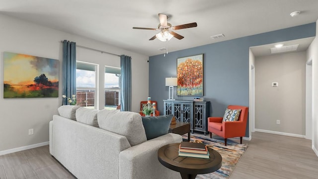 living room with ceiling fan, light wood-style floors, visible vents, and baseboards