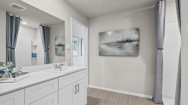 bathroom with baseboards, visible vents, wood finished floors, and vanity