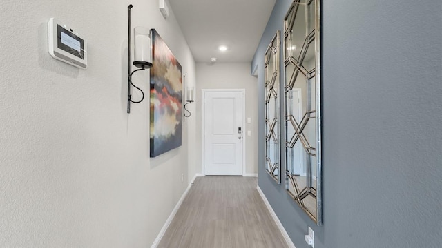 corridor featuring light wood-style flooring and baseboards