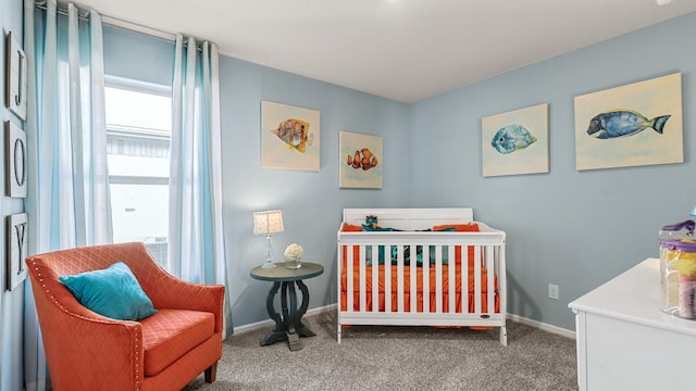 carpeted bedroom featuring a crib and baseboards