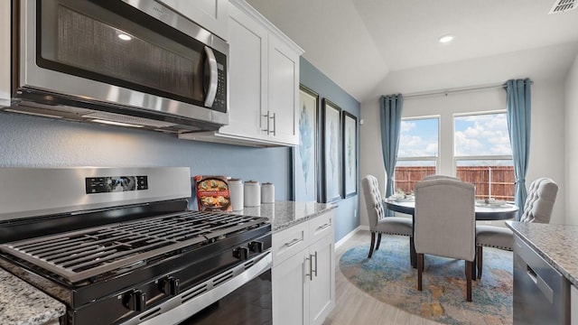 kitchen featuring visible vents, appliances with stainless steel finishes, light stone countertops, and white cabinets