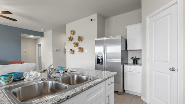 kitchen featuring ceiling fan, a sink, visible vents, white cabinets, and stainless steel fridge