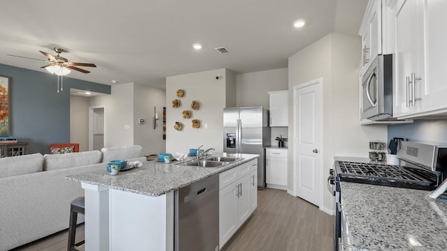 kitchen with open floor plan, appliances with stainless steel finishes, a sink, and white cabinets