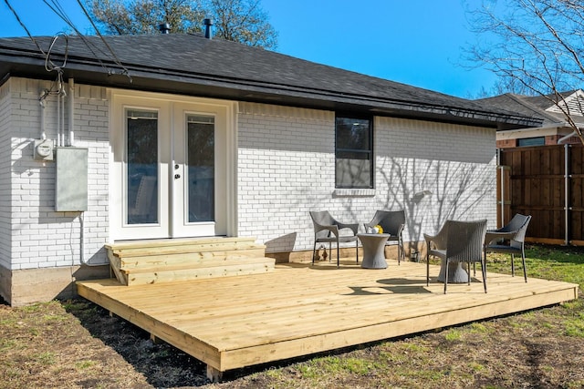 back of property featuring entry steps, french doors, fence, a wooden deck, and brick siding