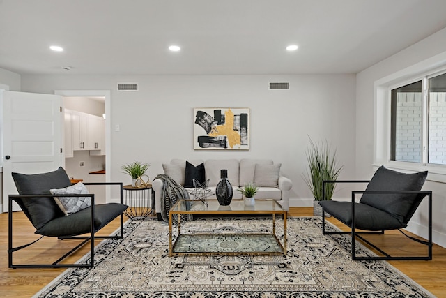 living area with light wood-style floors, recessed lighting, visible vents, and baseboards