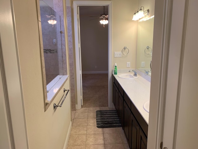 bathroom featuring tile patterned floors, a sink, tiled shower, double vanity, and baseboards