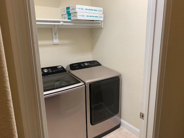 clothes washing area featuring baseboards, laundry area, and washing machine and clothes dryer