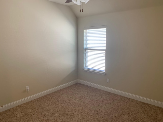 empty room featuring light colored carpet, baseboards, lofted ceiling, and a ceiling fan