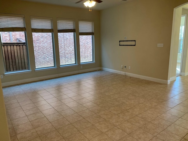 empty room with baseboards, arched walkways, and ceiling fan