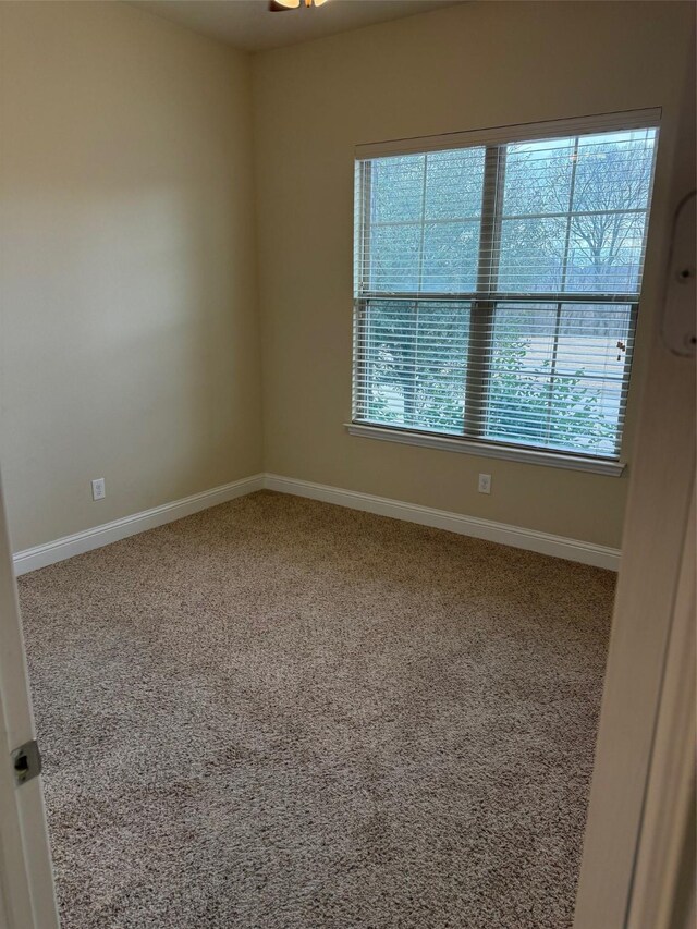 carpeted empty room featuring baseboards