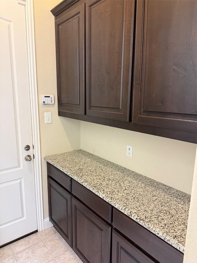 interior space featuring dark brown cabinets, baseboards, and light stone countertops