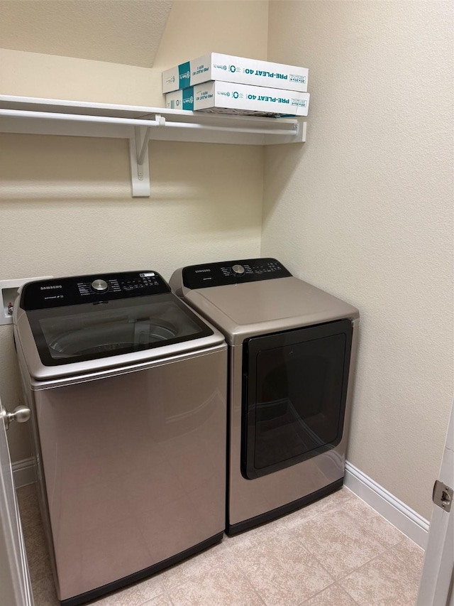 clothes washing area featuring baseboards, laundry area, and washing machine and clothes dryer