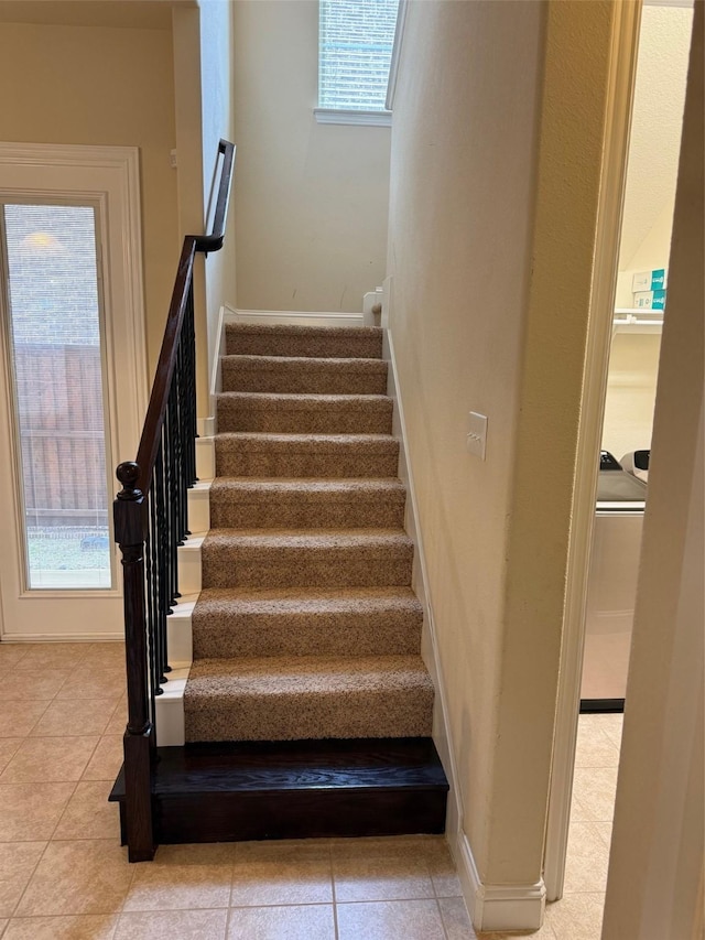 stairs featuring tile patterned flooring, plenty of natural light, and baseboards