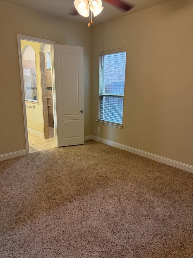 spare room with ceiling fan, baseboards, and light carpet