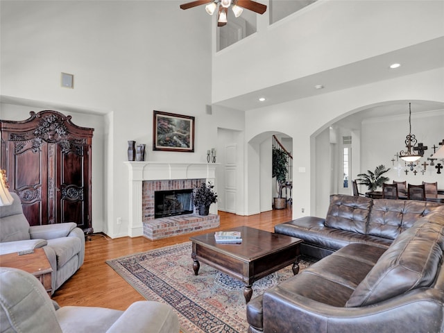 living room featuring ceiling fan, recessed lighting, a fireplace, wood finished floors, and arched walkways