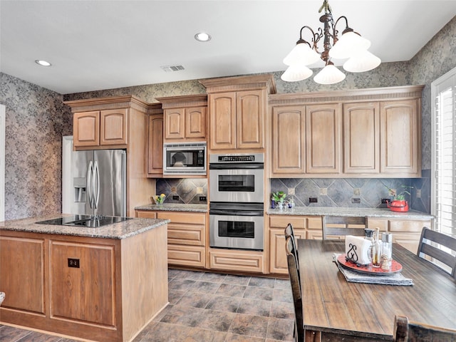 kitchen featuring visible vents, decorative light fixtures, appliances with stainless steel finishes, wallpapered walls, and light stone countertops