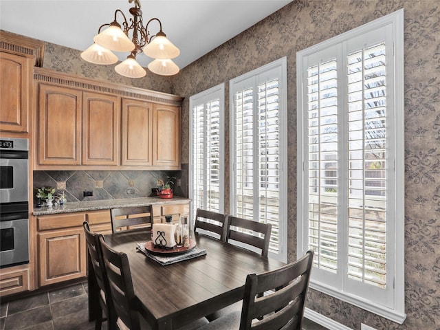 dining space with wallpapered walls and an inviting chandelier